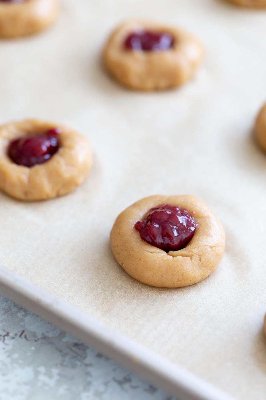 jam-filled pb&j vegan thumbprint cookies on a cookie sheet ready to be baked