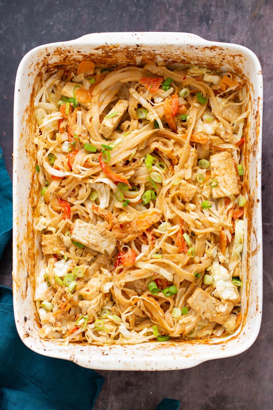 a white casserole dish with peanut butter noodles in a creamy peanut sauce with veggies and tofu
