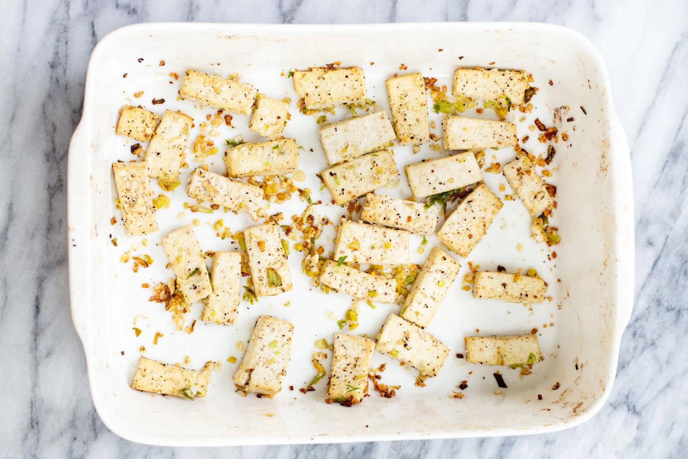 tofu cubes being baked with garlic and ginger in a casserole dish