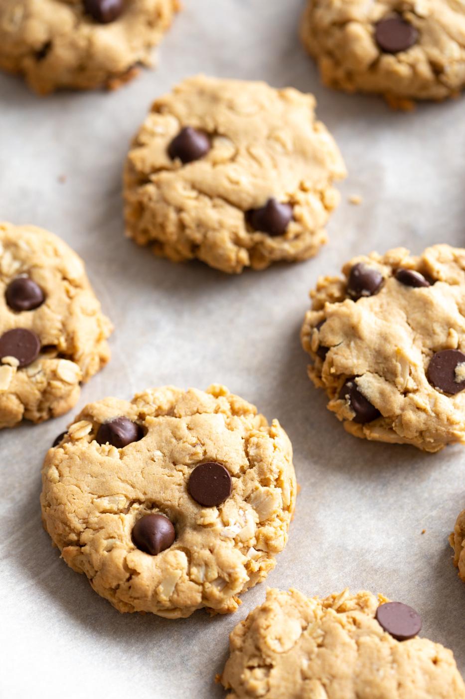 Vegan Peanut butter Oatmeal Chocolate chip Cookies on a parchment lined baking sheet