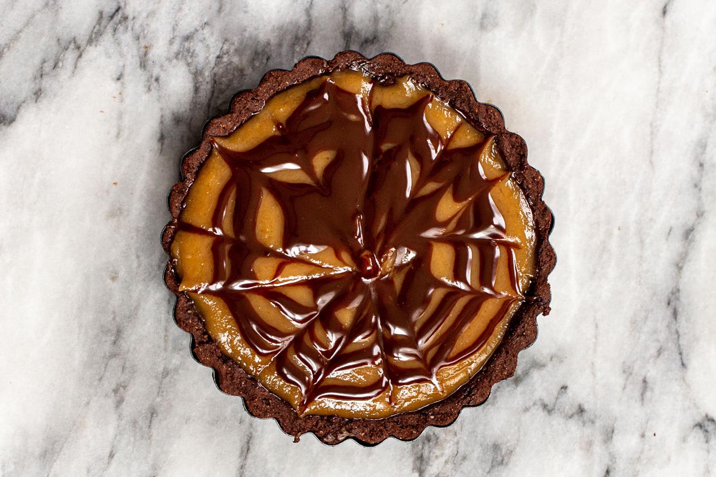 peanut butter chocolate mini tart decorated with a chocolate glaze pattern