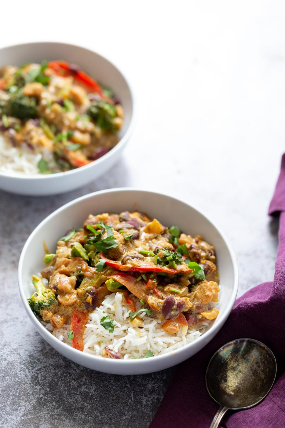 two bowls of vegan creamy coconut mild and kidney bean Peanut Stew served with rice