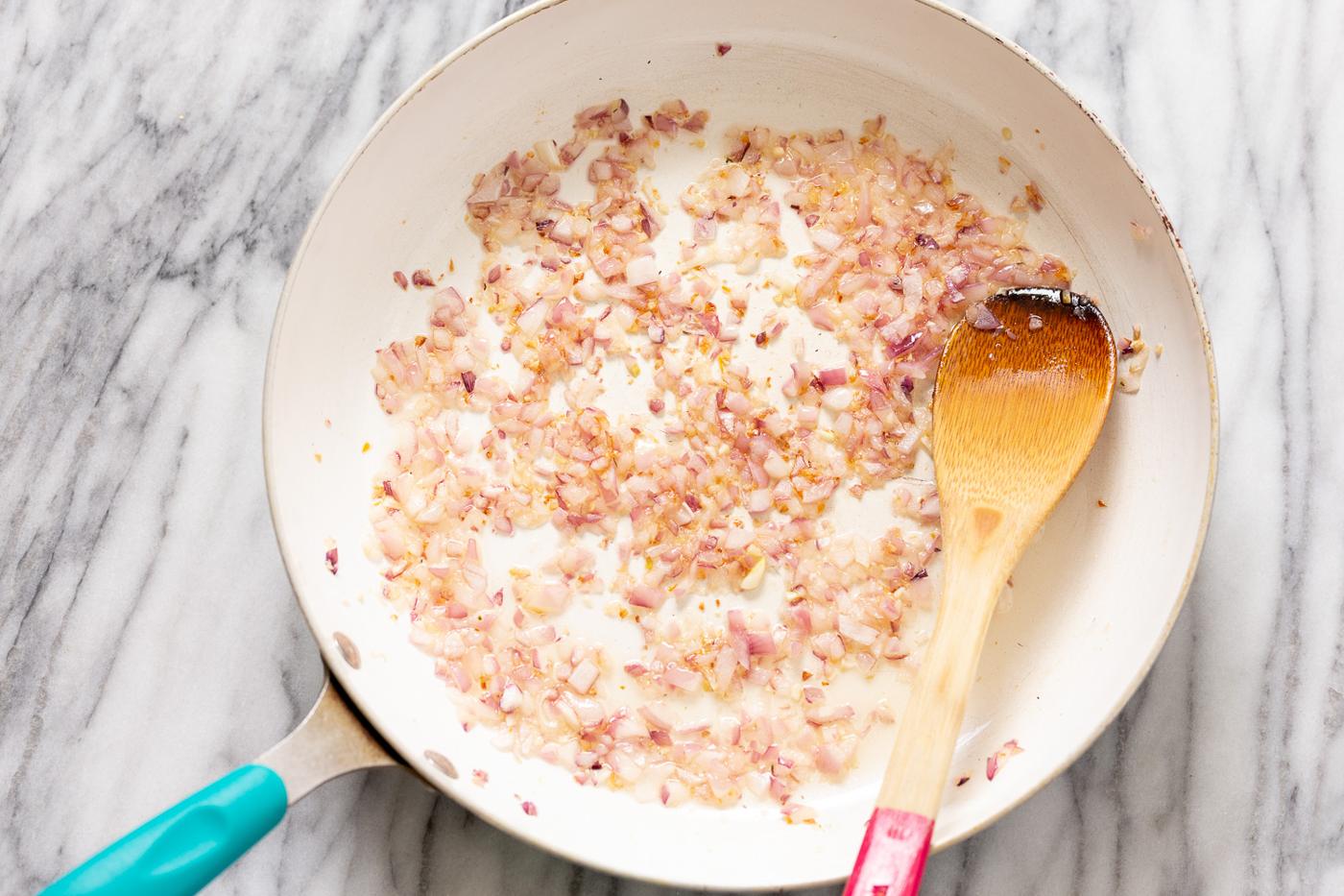 diced onion sauteeing in a frying pan for making peanut stew