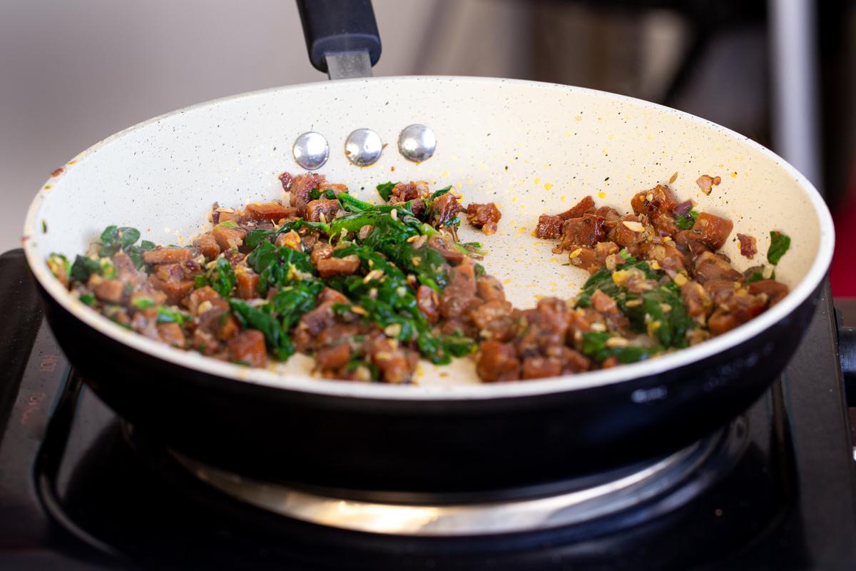 vegan sausage and spinach in a sauteeing pan