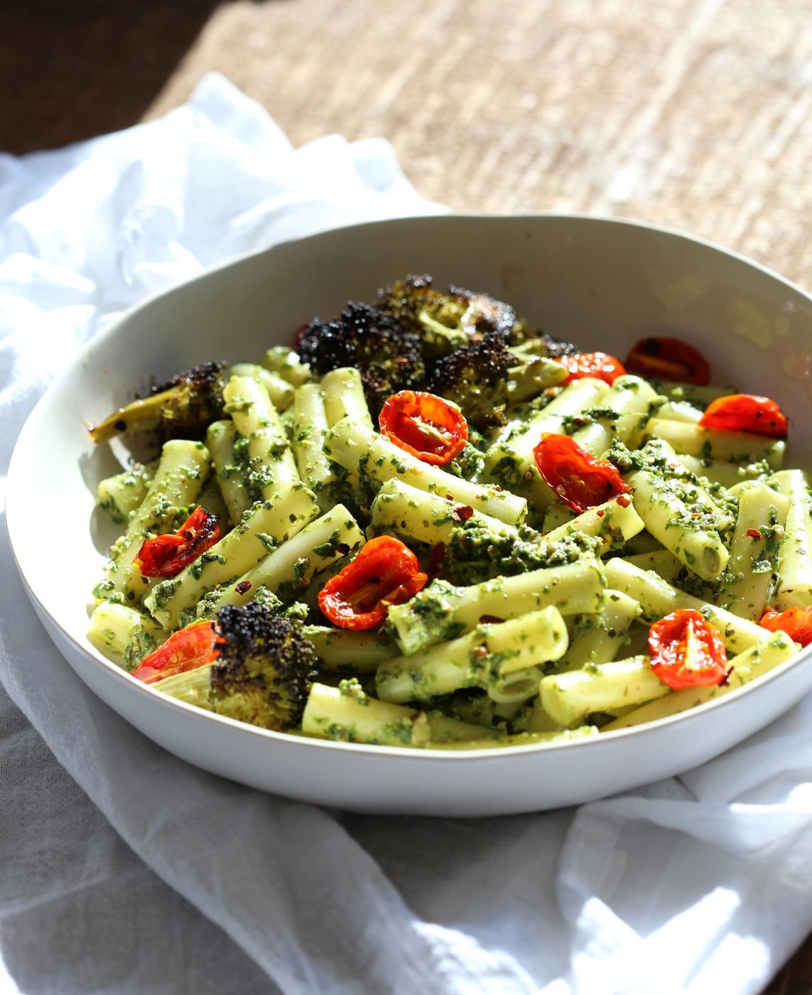 Large While Bowl with Vegan Pesto Pasta with Ziti, roasted cherry tomatoes and Charred broccoli on wood table