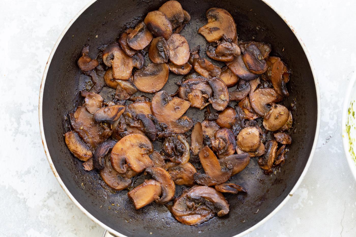 mushrooms sauteeing in a black pan