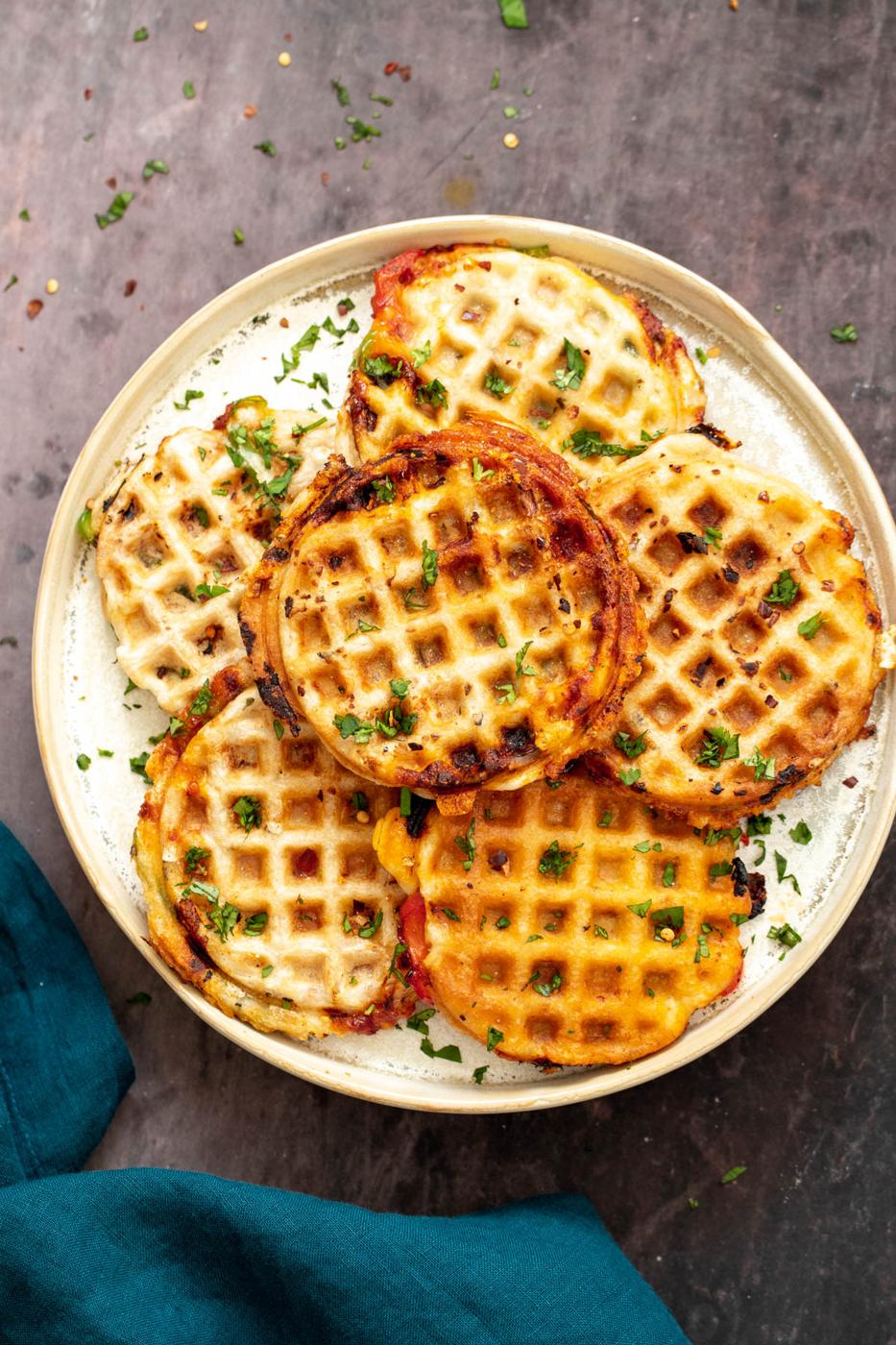 vegan pizza waffles on a white plate with a napkin on the side