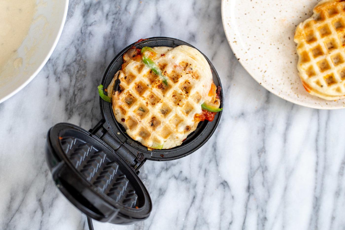 a freshly baked vegan pizza waffle in a waffle iron