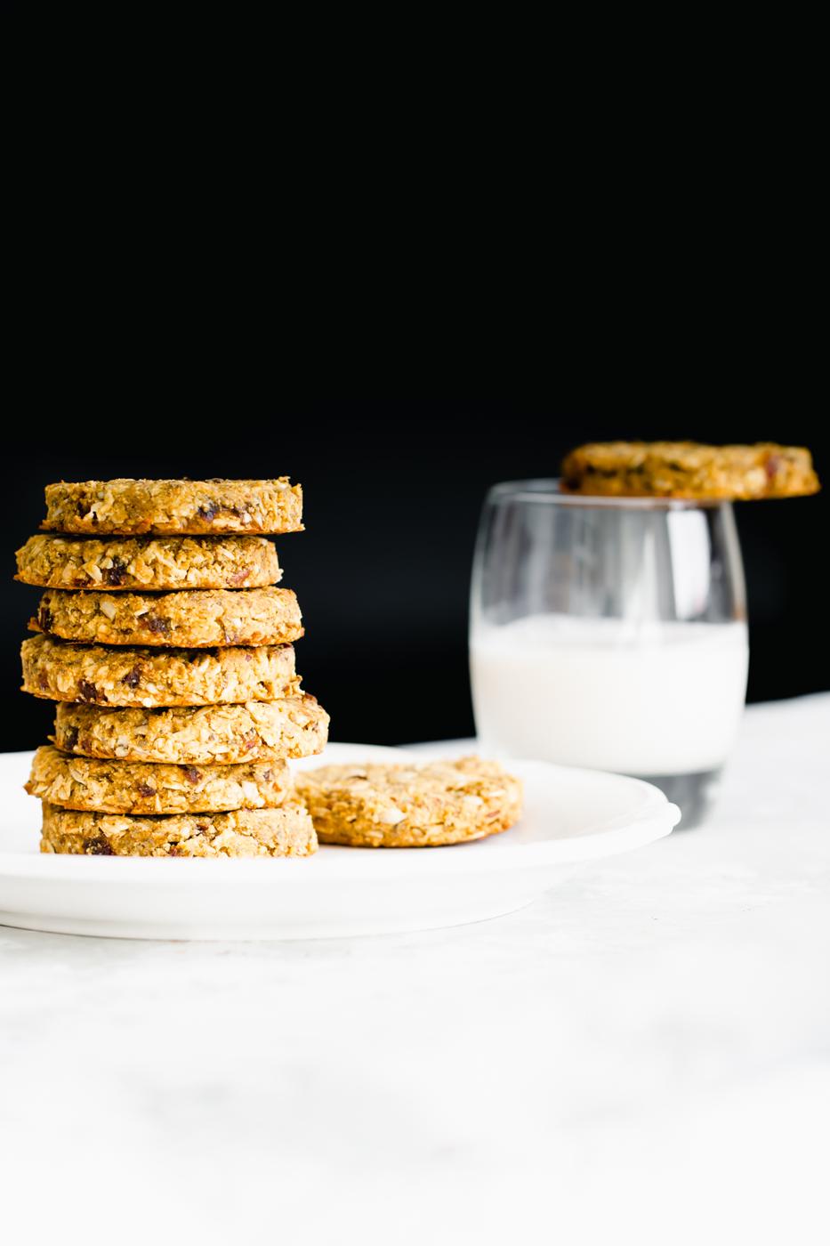 stacked pumpkin breakfast cookies on a white plate with a glass of milk in the background