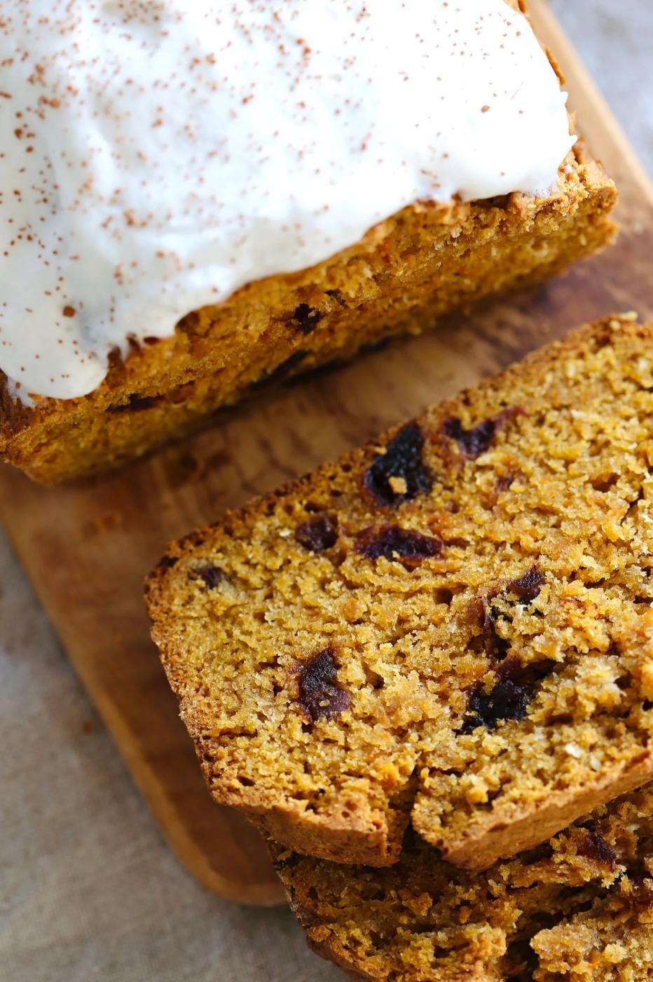 a sliced loaf of vegan pumpkin carrot bread on a wooden cutting board