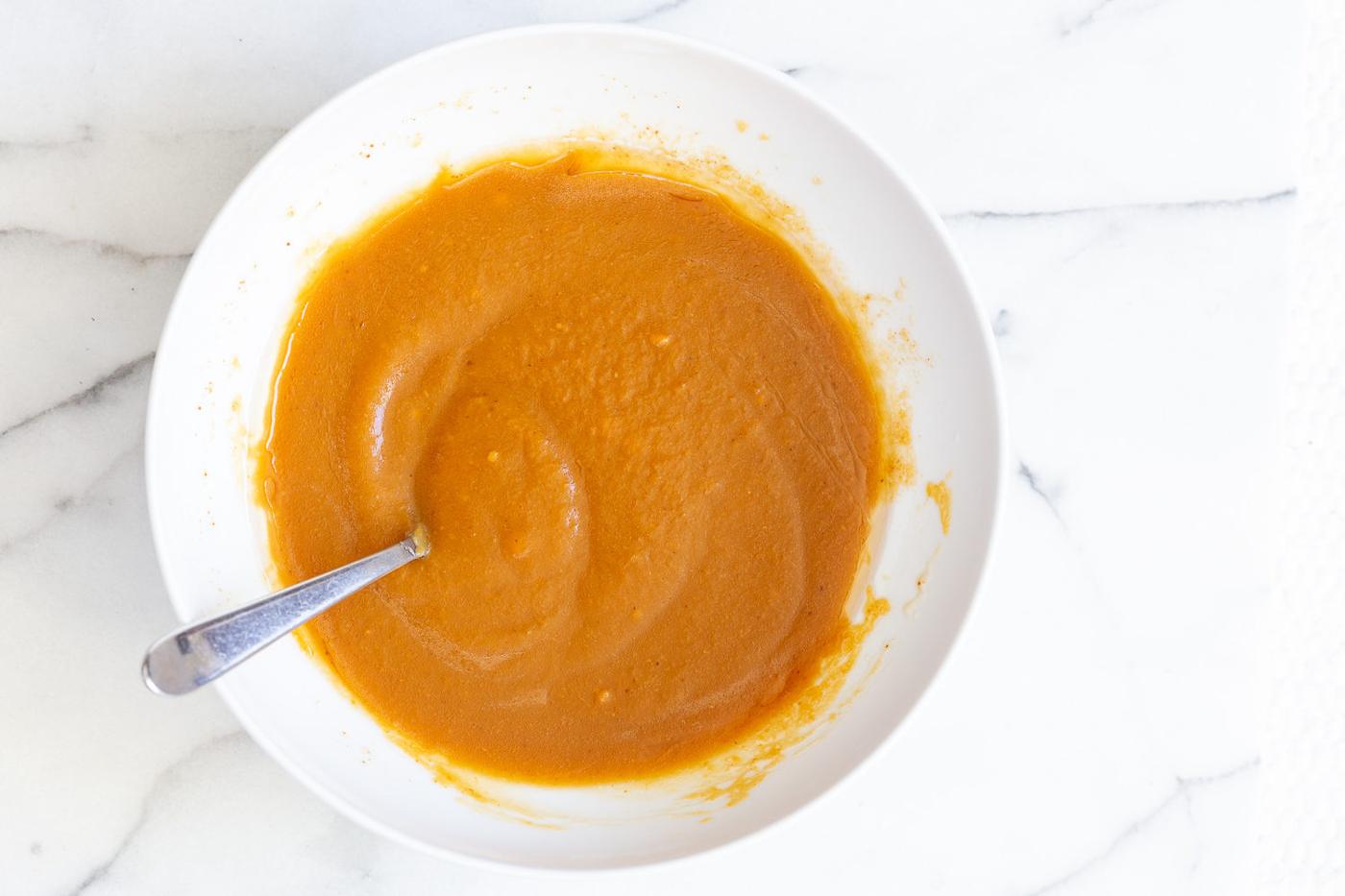 vegan pumpkin carrot bread batter being stirred in a bowl