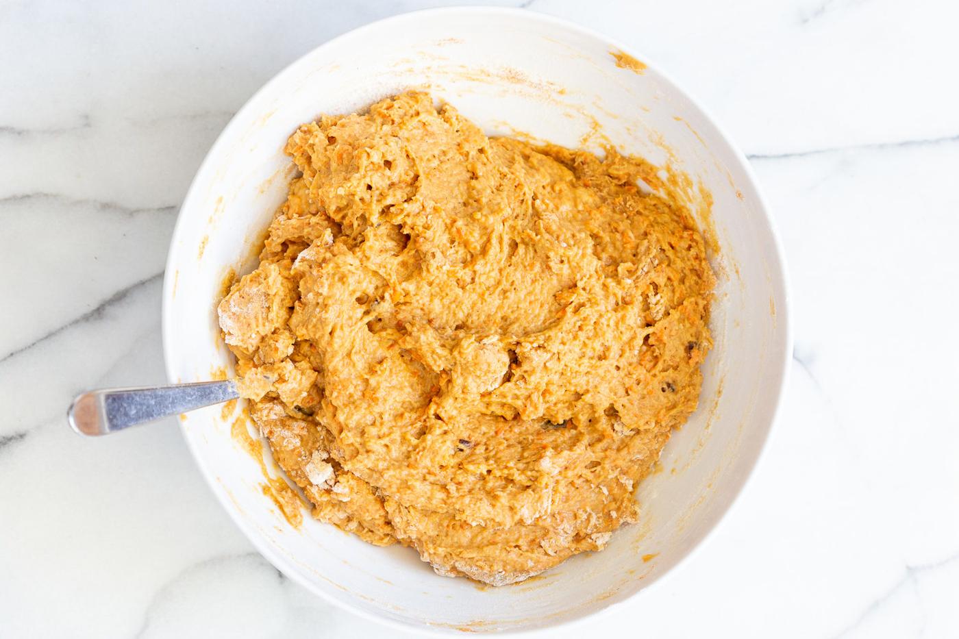 stiff vegan carrot bread batter in a mixing bowl with a spoon