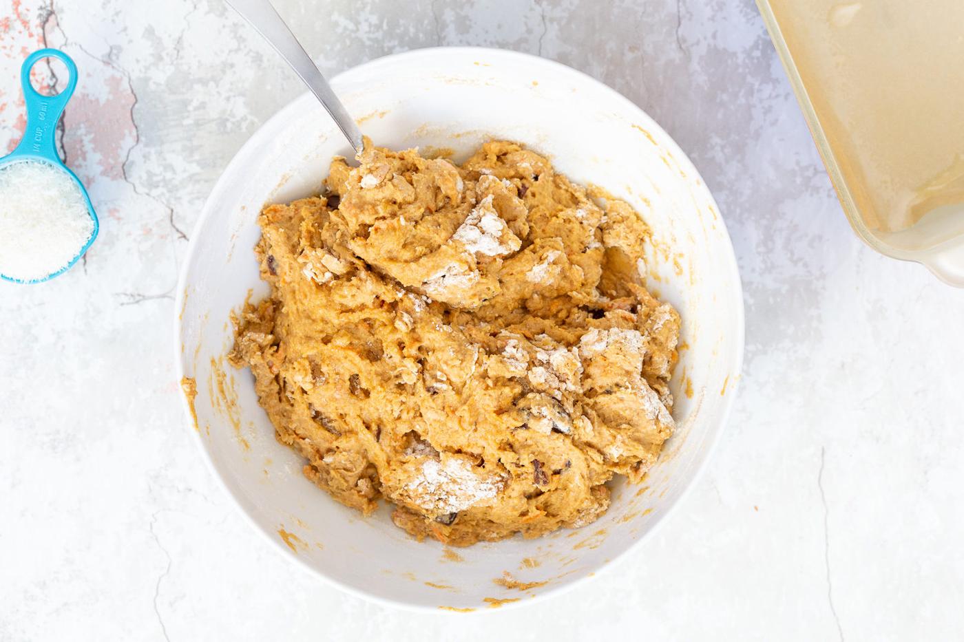 more flour being added to pumpkin bread batter to make it thicker