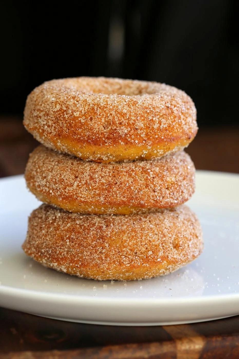 Vegan Pumpkin Donuts dusted with Cinnamon Sugar on a white plate