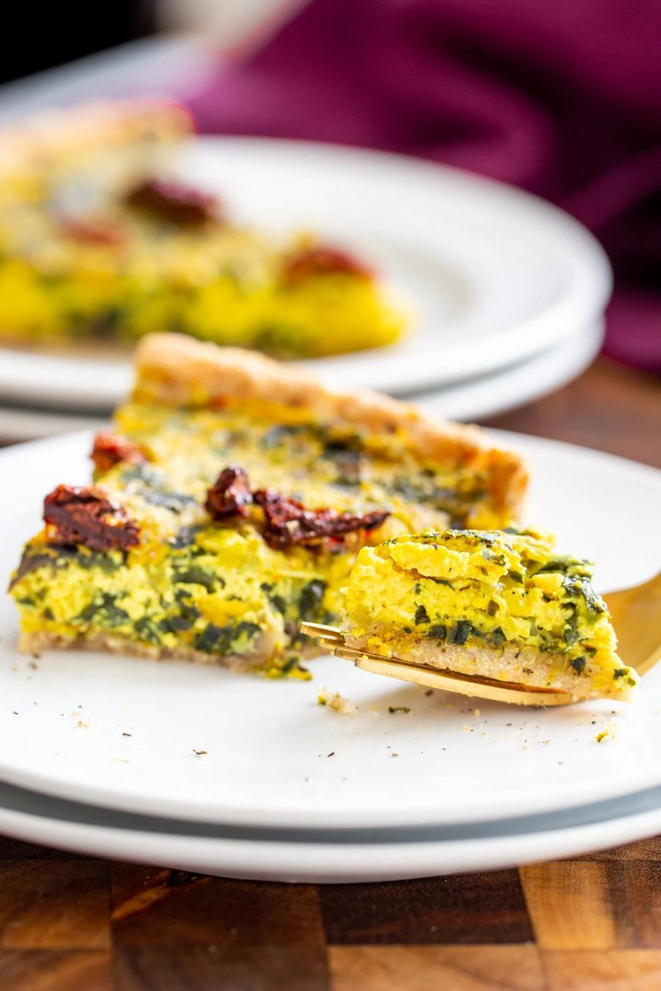 a fork taking out a piece of a slice of vegan quiche