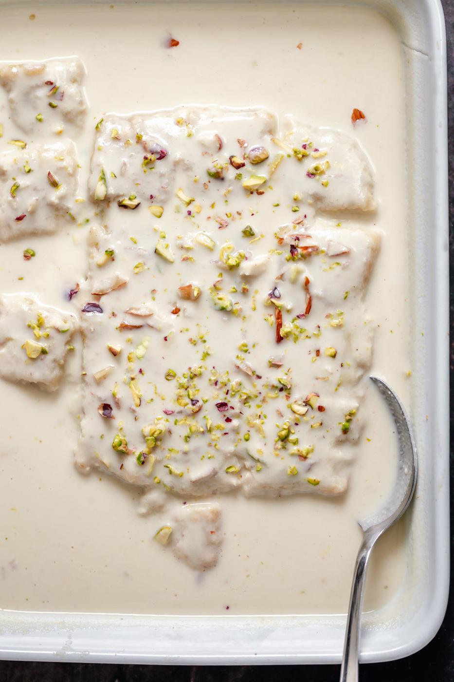 casserole dish with vegan rasmalai cake with a spoon