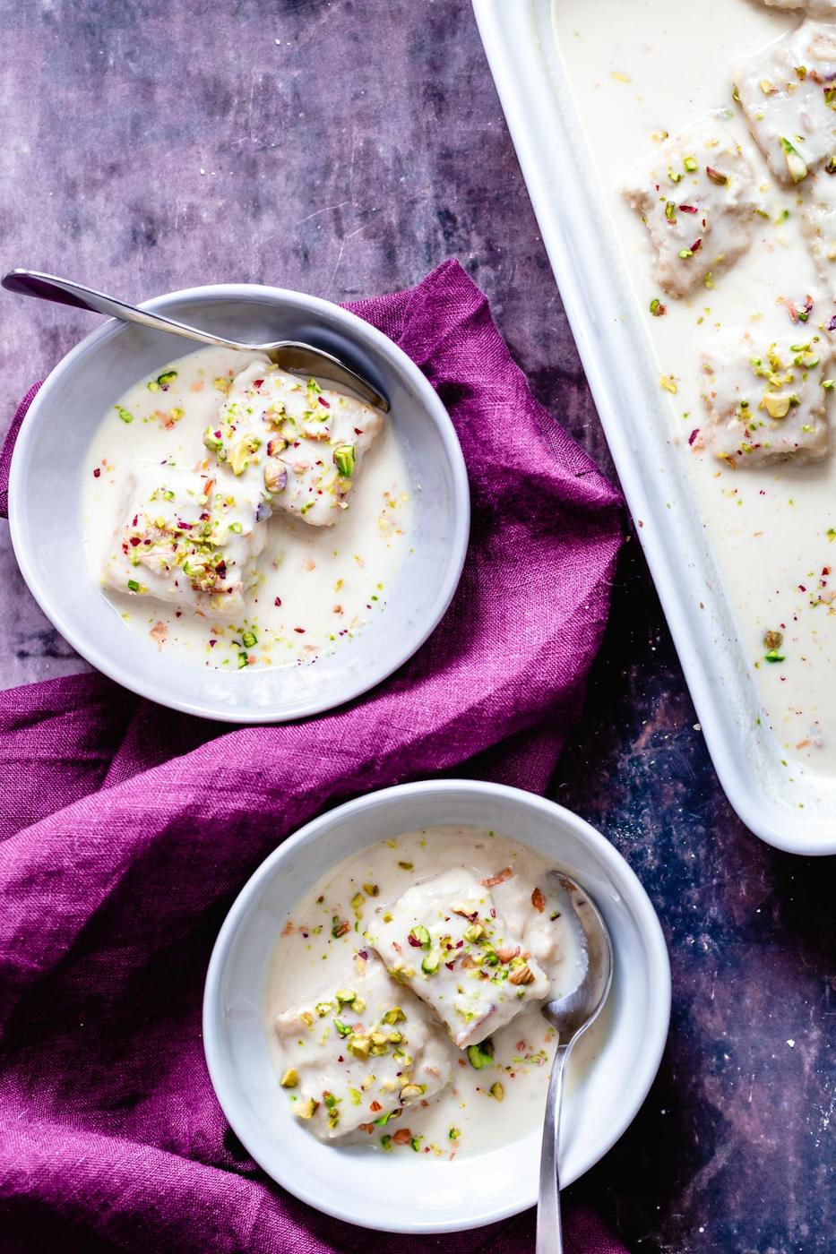 two small bowl of vegan rasmalai cake immersed in vegan nut milk sauce