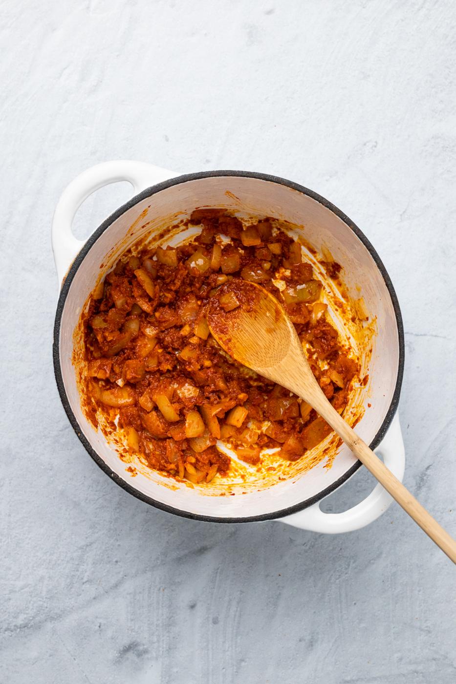 onions being sauteed with red curry paste