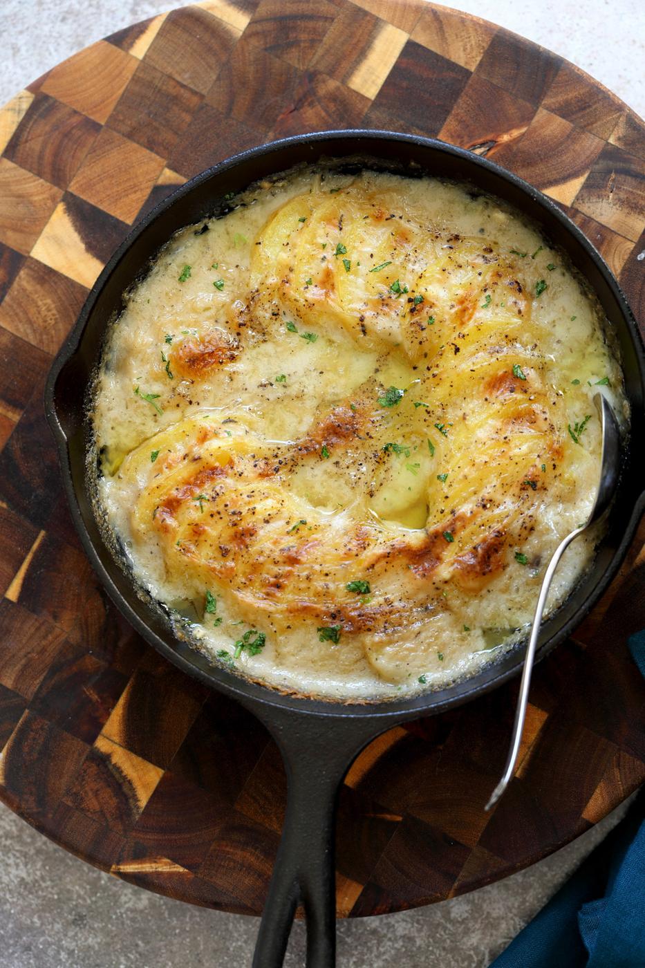 Vegan Scalloped Potatoes in a cast iron skillet on wood board