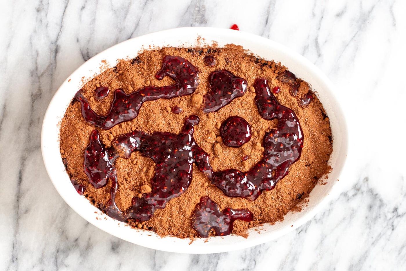 cherry perserved being added to chocolate pudding cake