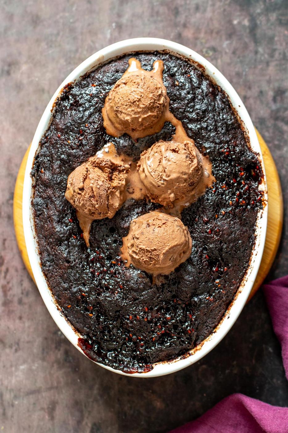 vegan self saucing chocolate pudding cake in a round casserole dish topped with ice cream