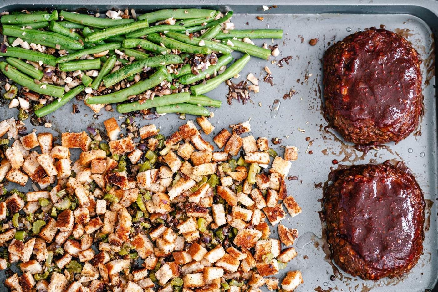 baked vegan stuffing and green beans next to two small lentil meatloaves