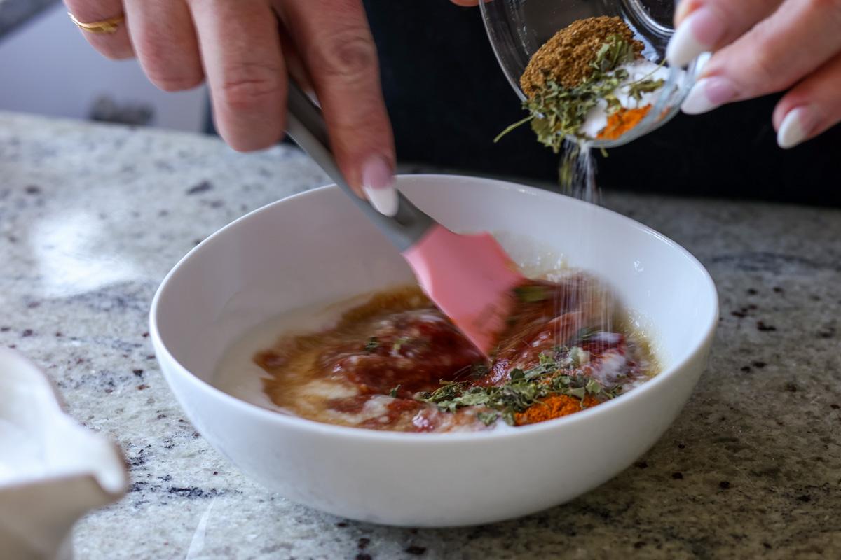 adding herbs and spices to the sauce