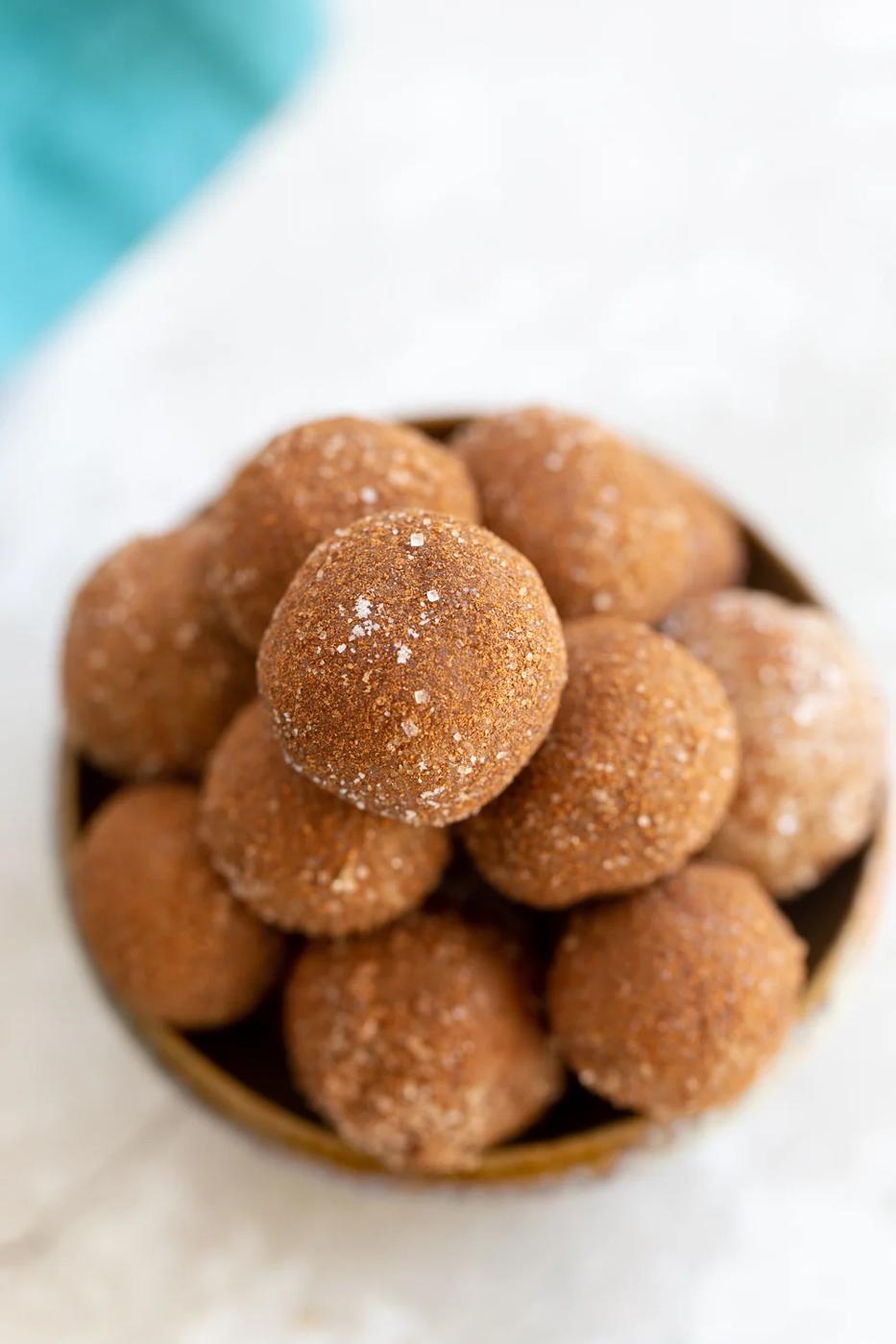 overhead shot of a clay bowl with vegan Snickerdoodle bites rolled in cinnamon sugar