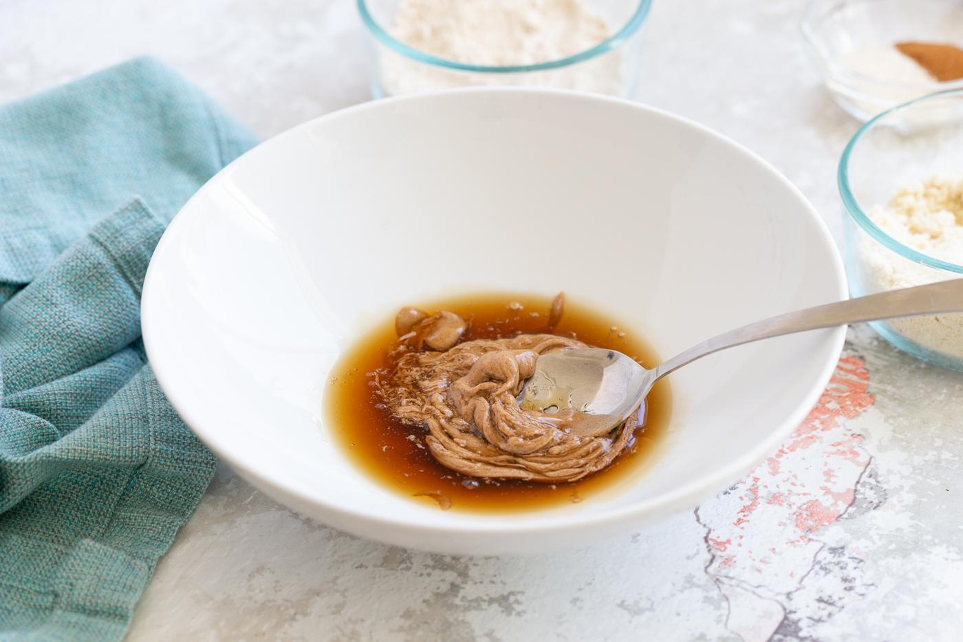 maple syrup and nut butter being stirred together in a small bowl