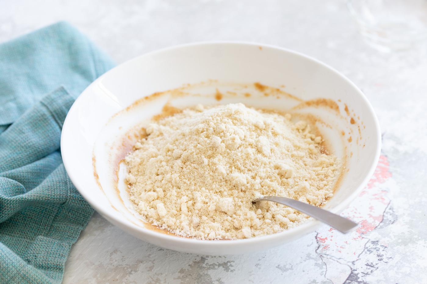 oat flour and ground nuts being mixed with nut butter for making snack bites