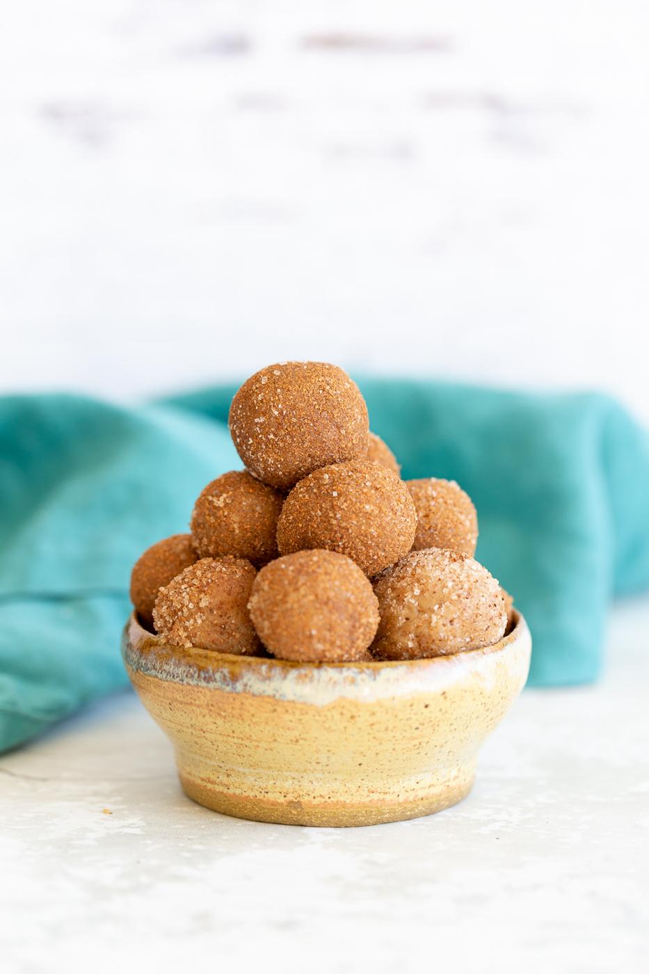 a small bowl with healthy Vegan Snickerdoodle Bites with a blue kitchen towel