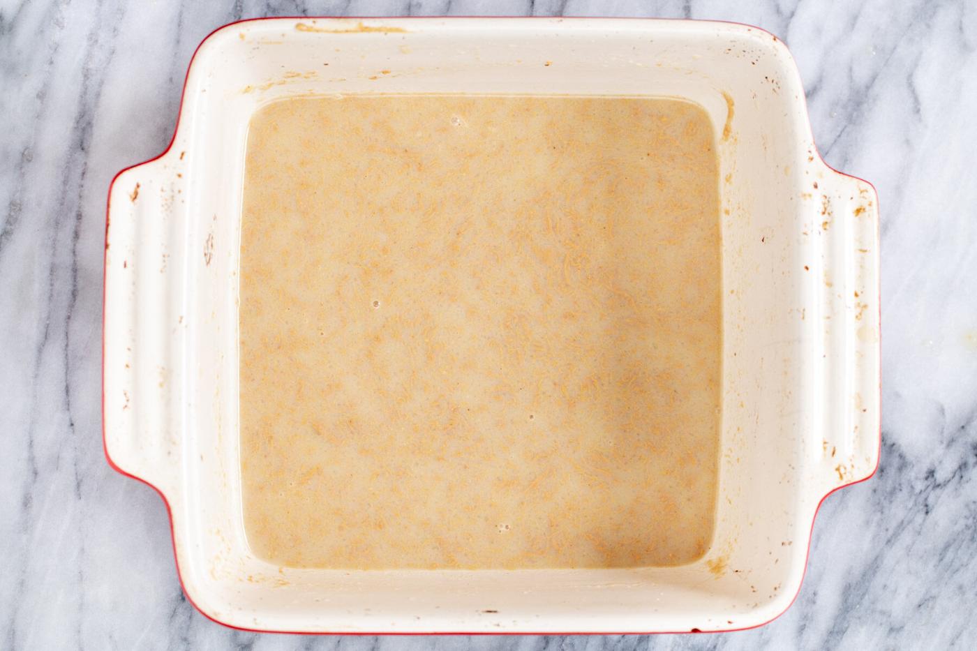 peanut butter being dissolved in hot milk in a casserole dish