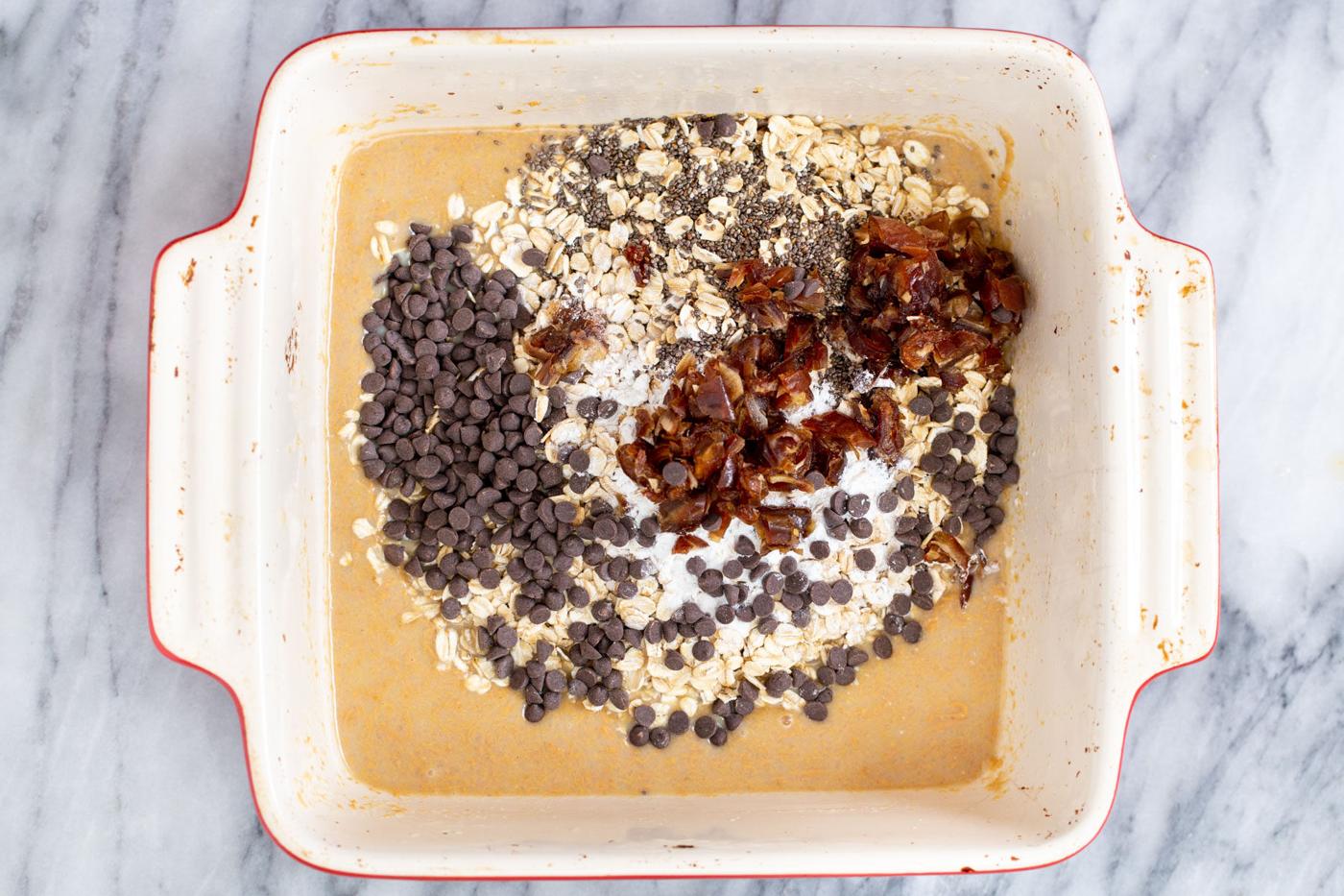 a casserole dish with oatmeal, chocolate chips, dates and chia seeds