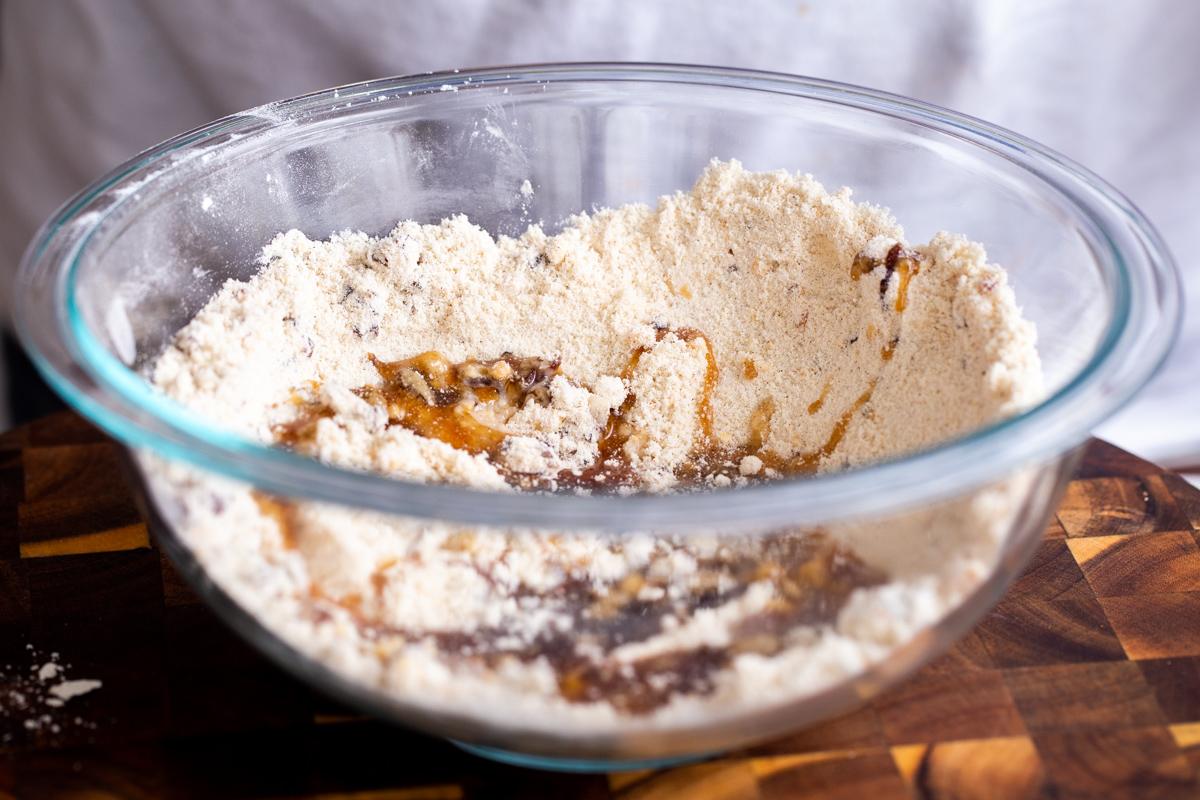 maple sryrup being added to dry ingredients in glass bowl