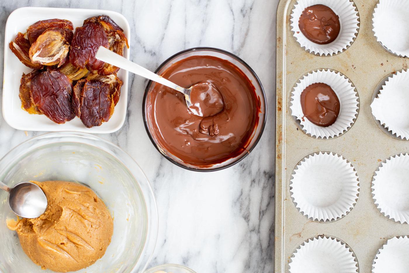 melted chocolate being spread into molds to make vegan snickers cups