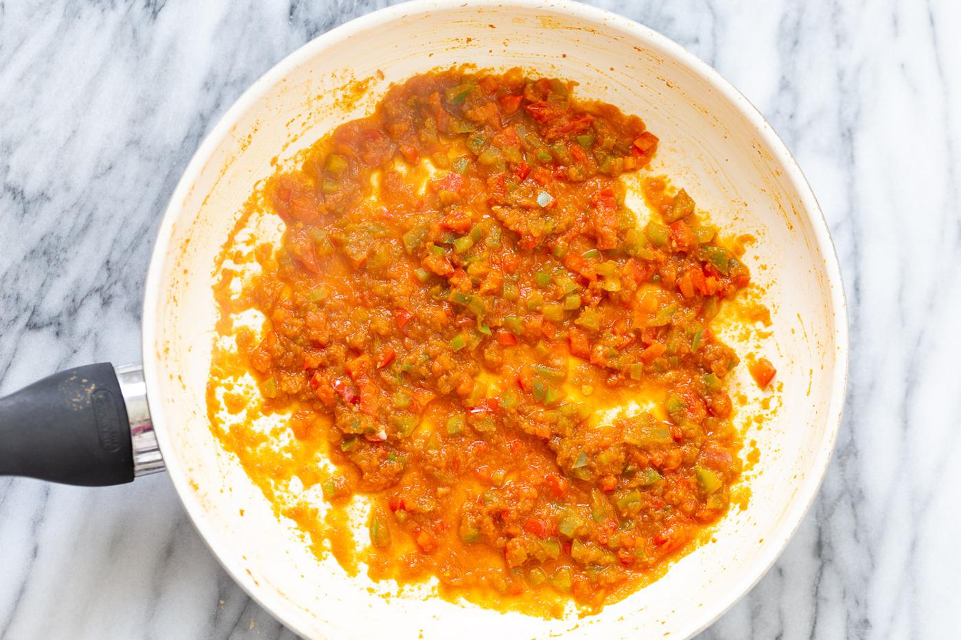 overhead shot of reduced tomato and bell pepper sauce in a white sauce pan