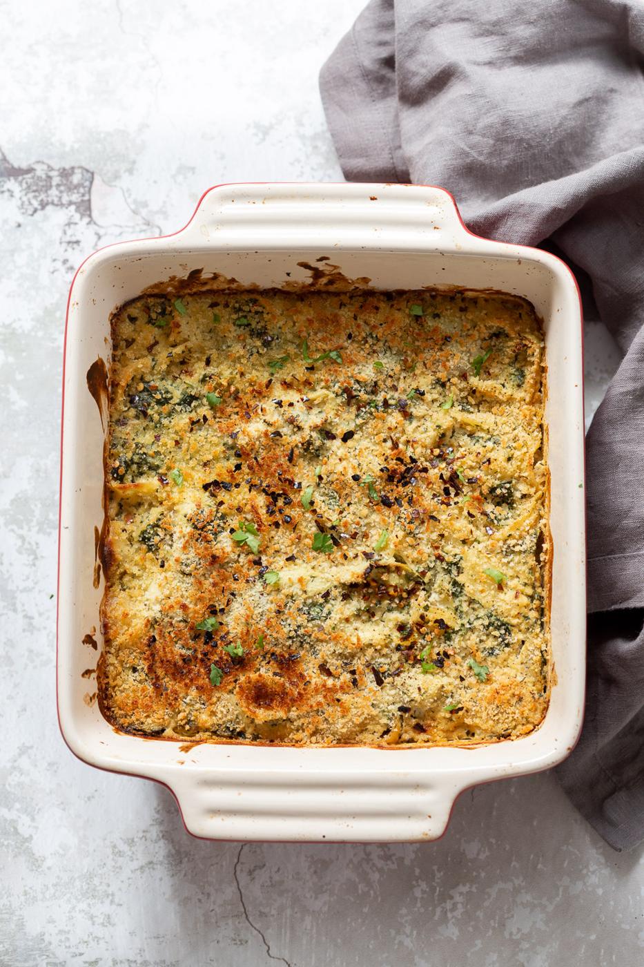 overhead shot of a vegan spinach and artichoke pasta bake with breadcrumb topping