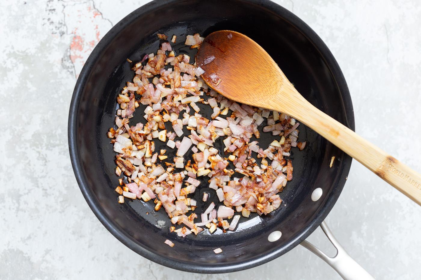 chopped onions being sauteed in a black skillet