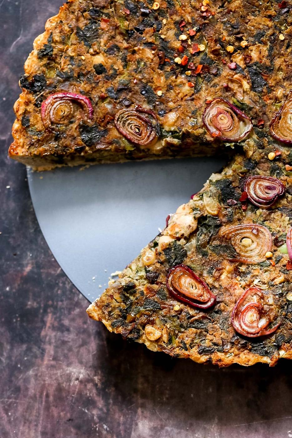 overhead shot of a vegan spinach mushroom tart topped with onions