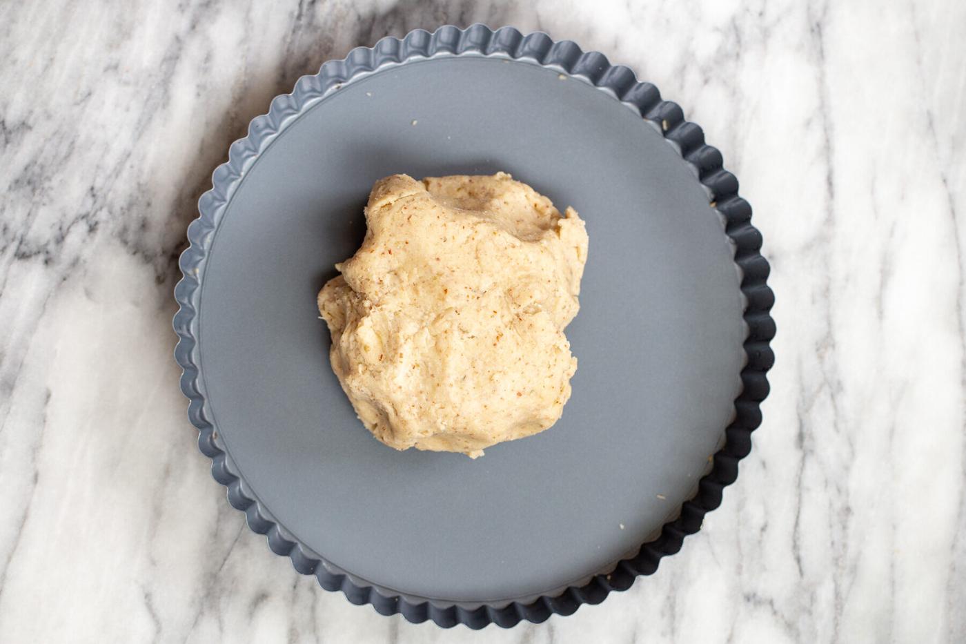 vegan savory pastry bein placed in a tart pan with removeable bottom