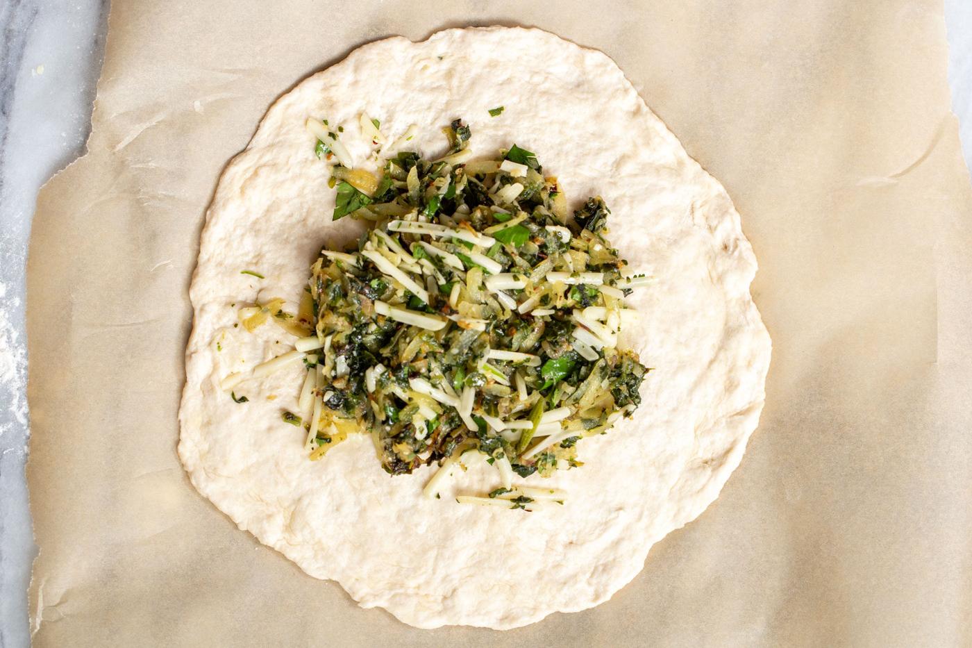 vegan spinach potato filling being spoon onto naan bread to