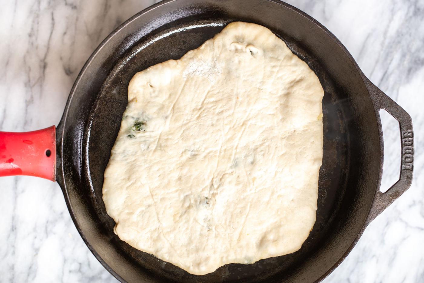 stuffed spinach naan being added to a skillet