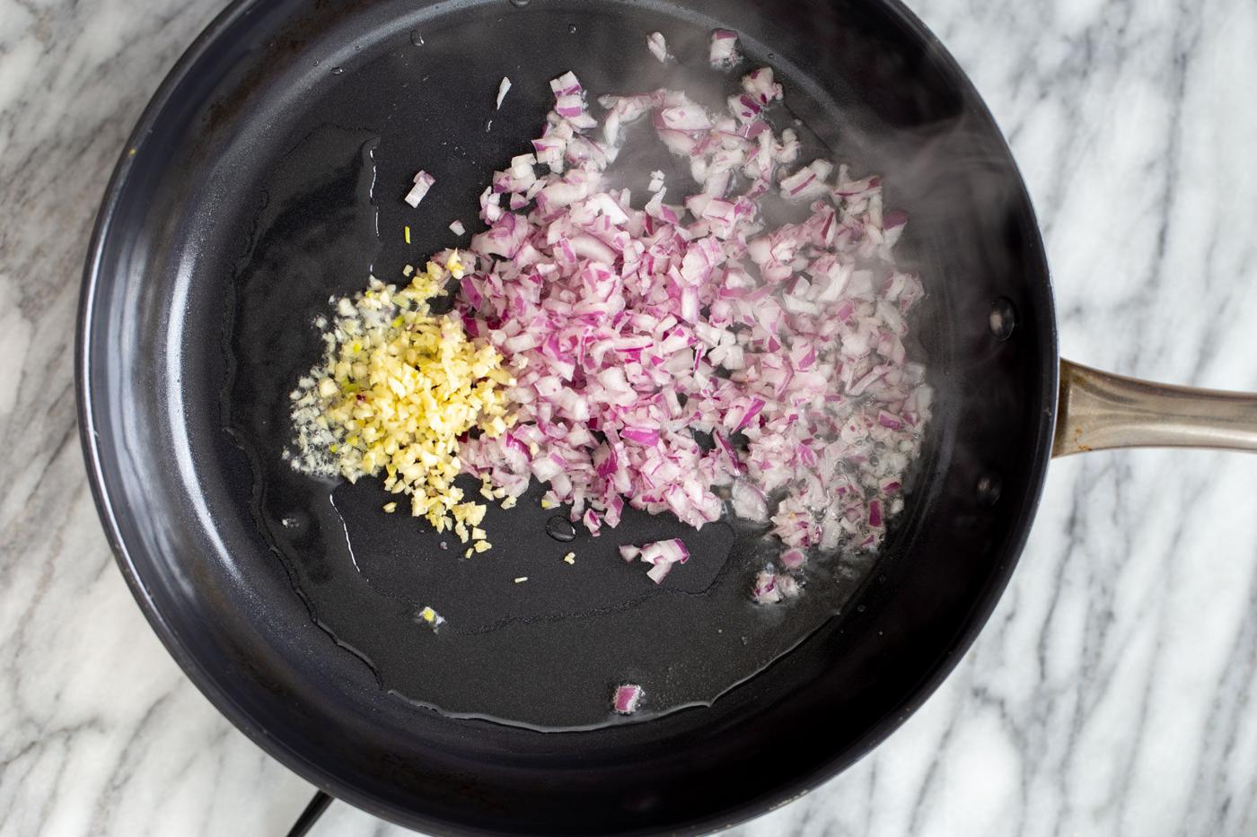 onions and garlic sauteing in a black skillet