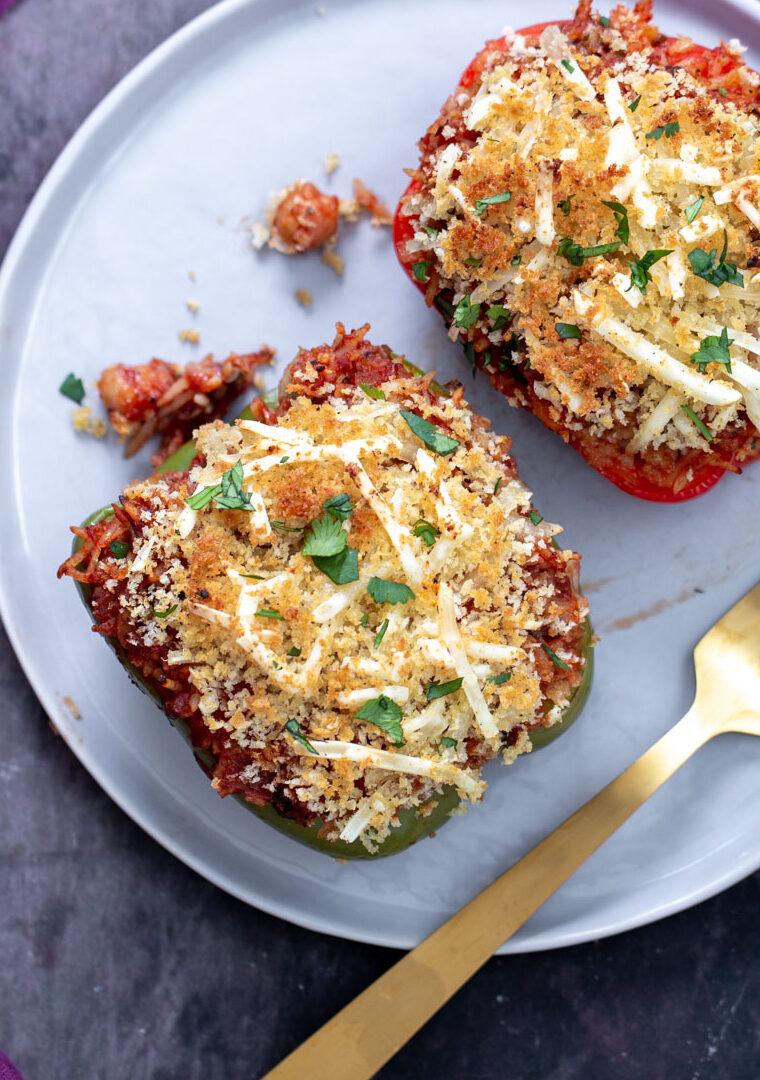 two stuffed bell peppers filled with rice and topped with cheese and bread crumbs