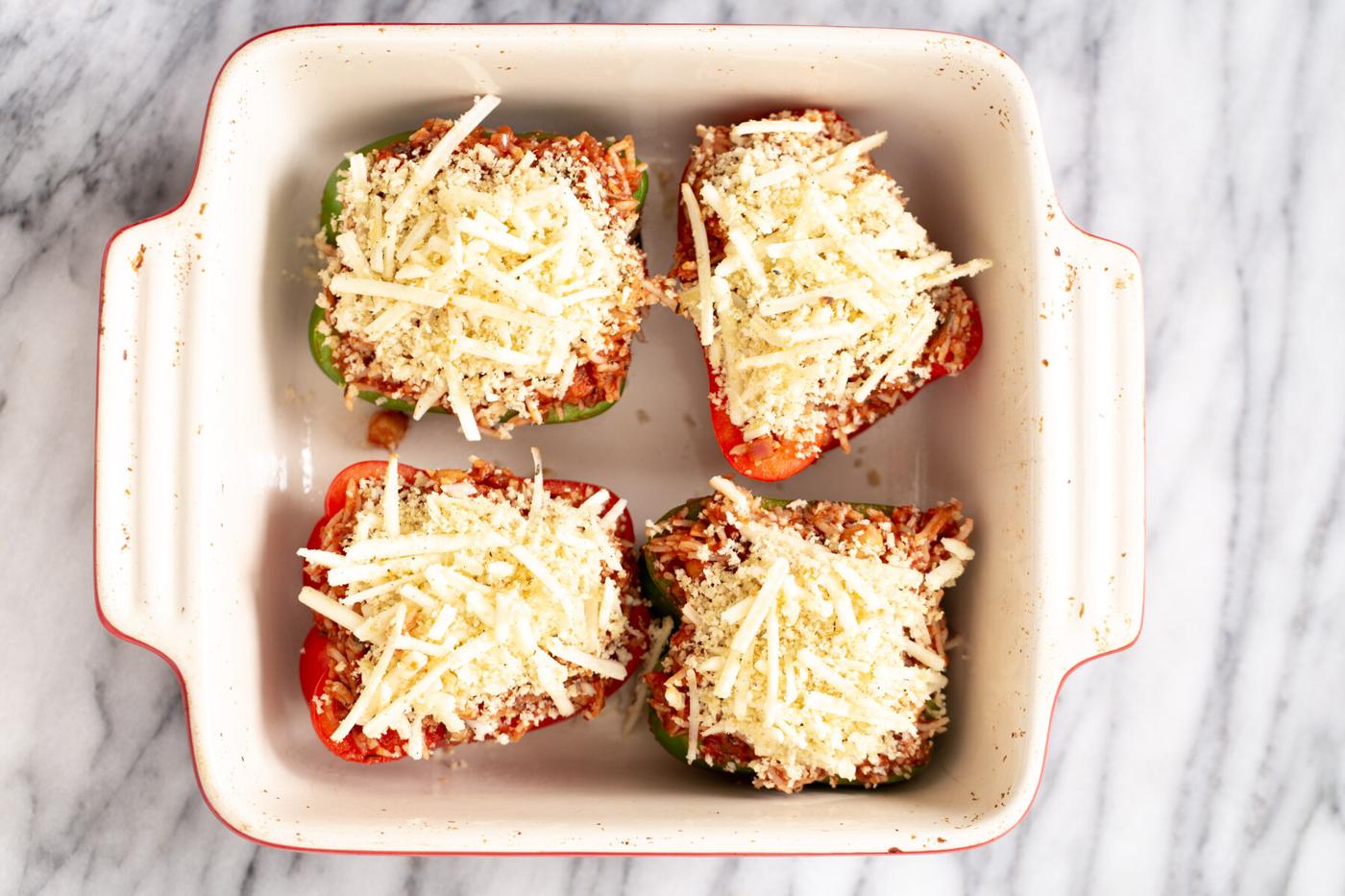 vegan stuffed bell peppers topped with cheese in a white casserole dish