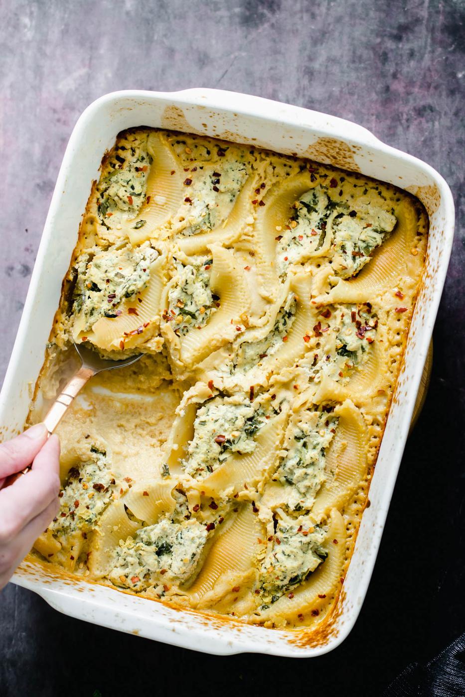 vegan ricotta stuffed shells being served with a silver serving spoon