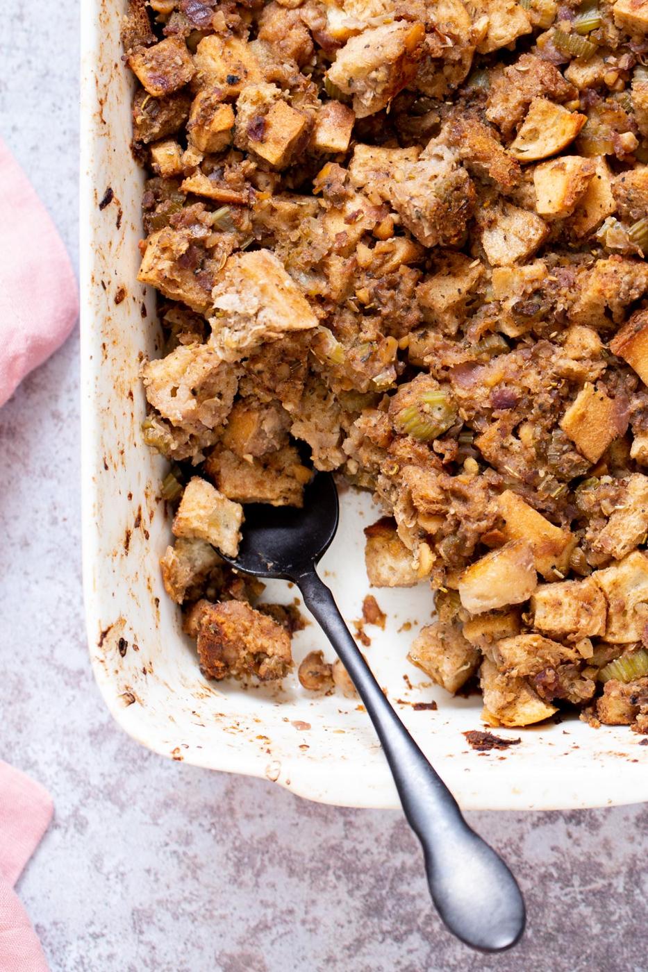 vegan stuffing in a white casserole dish with a spoon