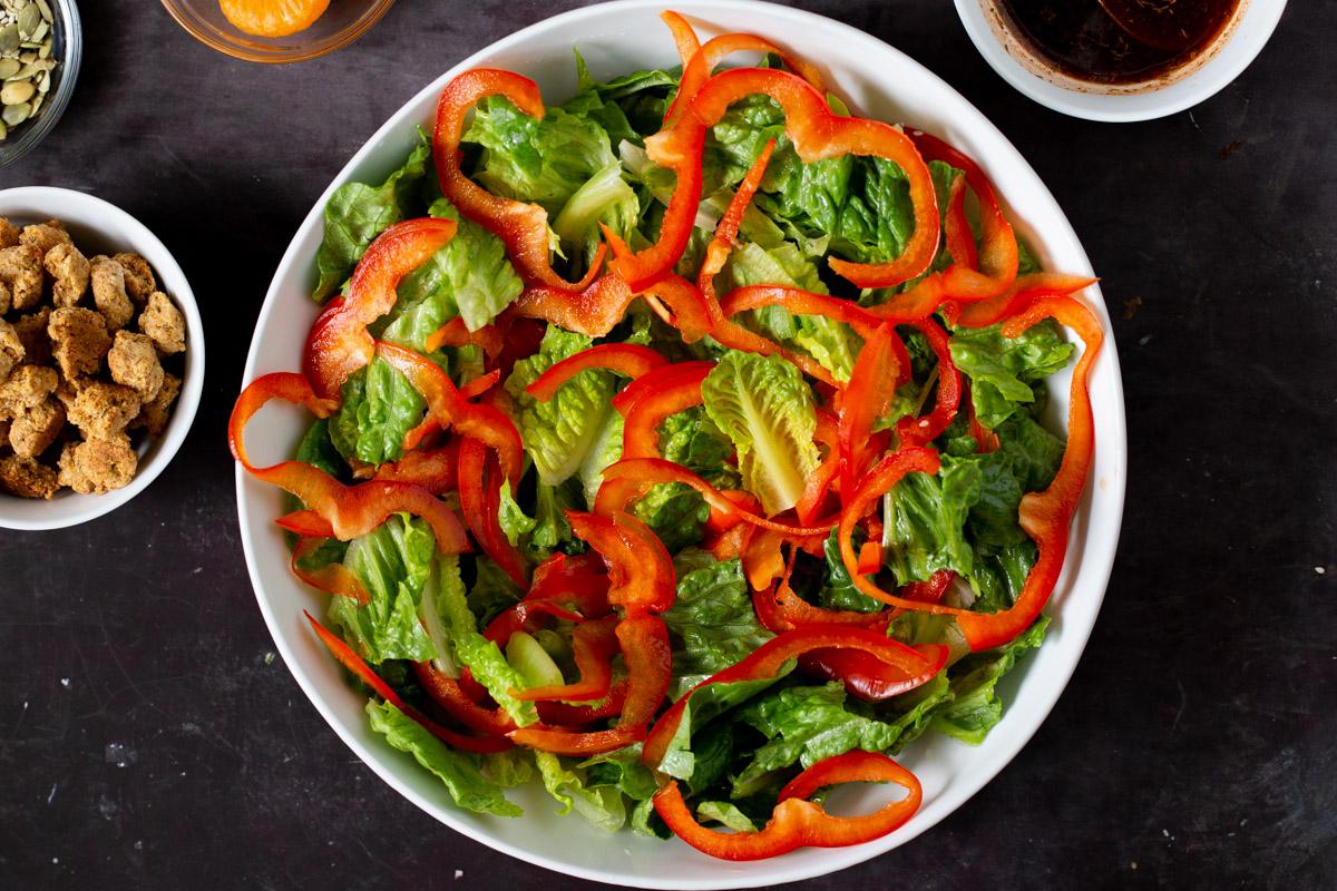 adding red pepper to the salad bowl