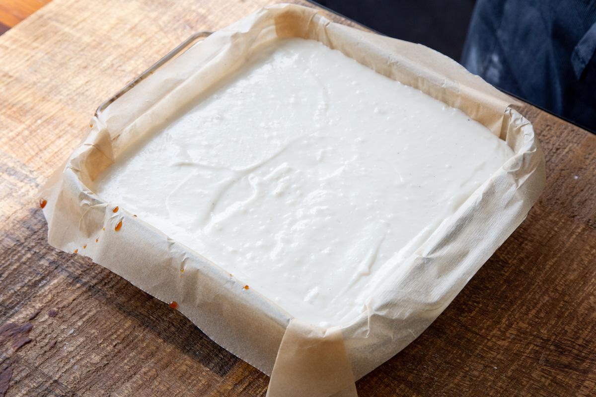 vegan mascarpone cream being poured over baked sponge cake