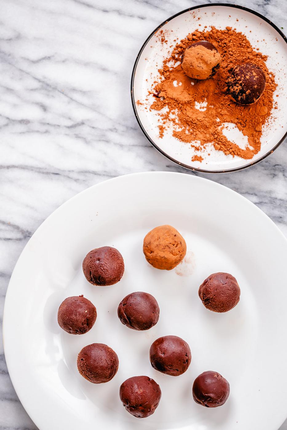 vegan tiramisu truffles being rolled in cocoa powder